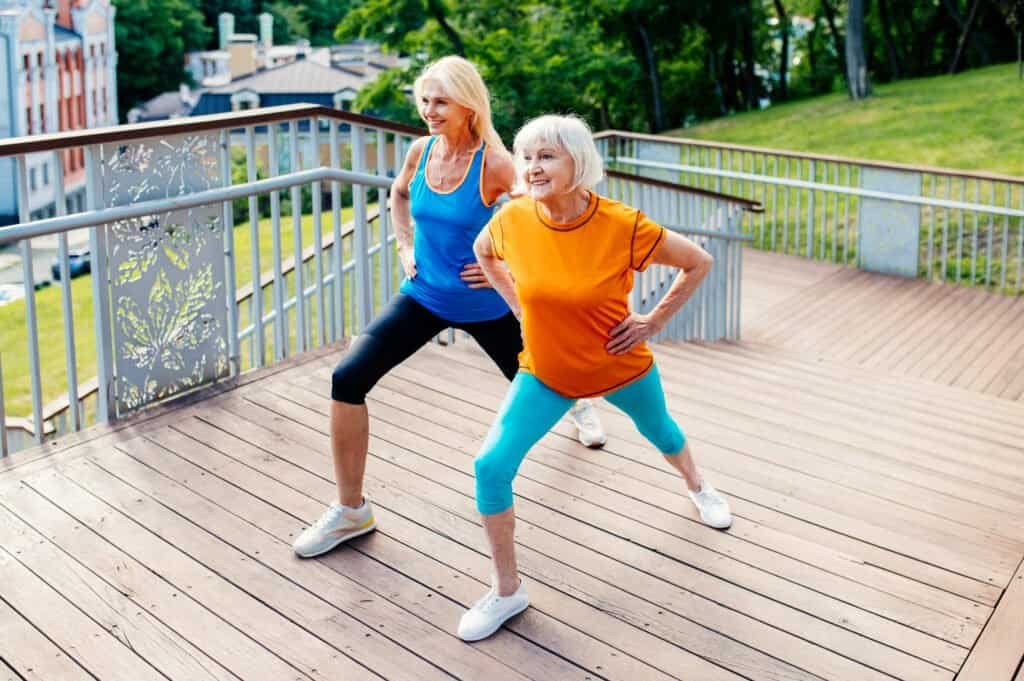 Group of beautiful sportive senior women training outdoors - Mature adults old friends doing fitness workout exercises in a park to stay healthy and fit