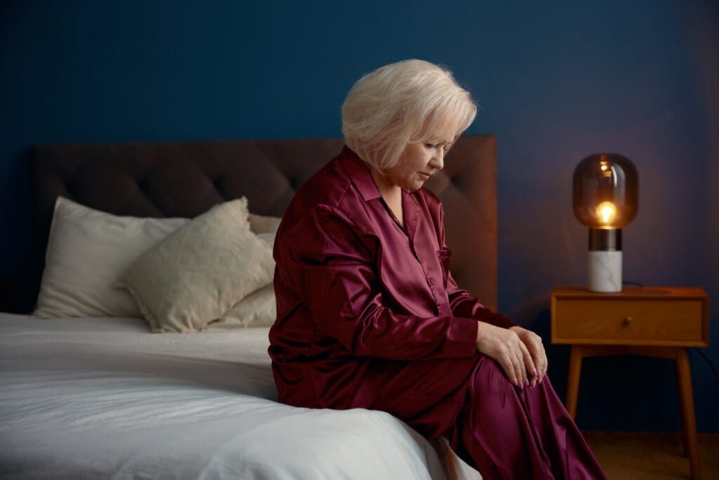 Elderly woman siting on the edge of deb