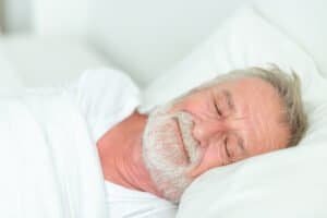 Happy Senior Man Sleeping In Bed.