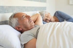 Senior Man And Woman Sleeping On Bed.