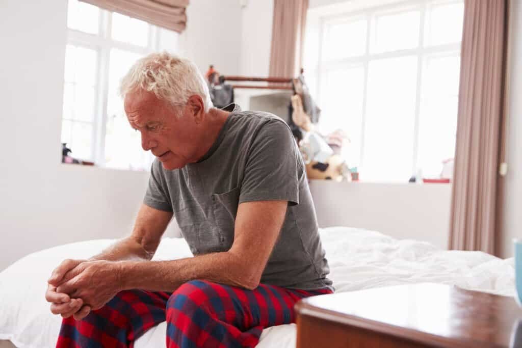 Senior Man Sitting On Bed At Home Suffering from Nocturia