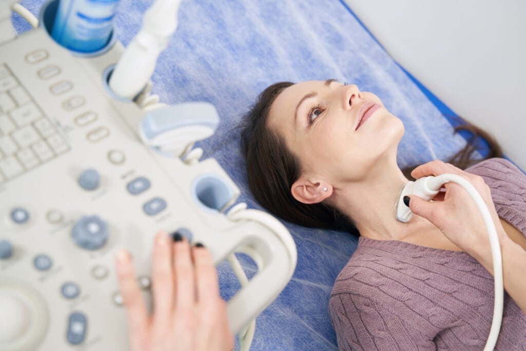 Calm young Caucasian woman lying during diagnostic medical procedure performed by sonographer