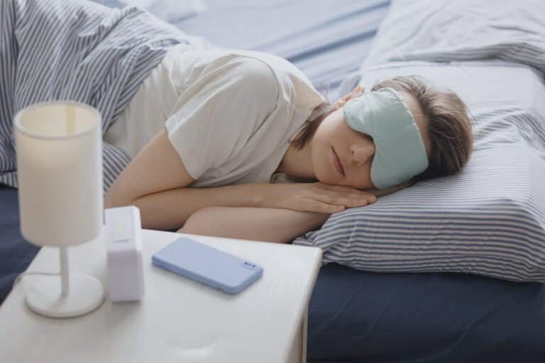 woman in bed with a sleep mask wakes up and turns off the alarm. a clock
