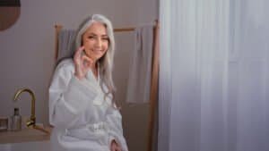 Aged senior mature lady Caucasian old gray-haired woman female in bathrobe in bathroom after washing beauty procedure showing ok recommend gesture happy satisfied with anti-aging lifting skin care. High quality 4k footage