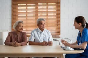 Asian caregiver nurse examine senior man and woman patient at home. Attractive young specialist career female support give advise and consult to older elderly mature couple in living room in house.