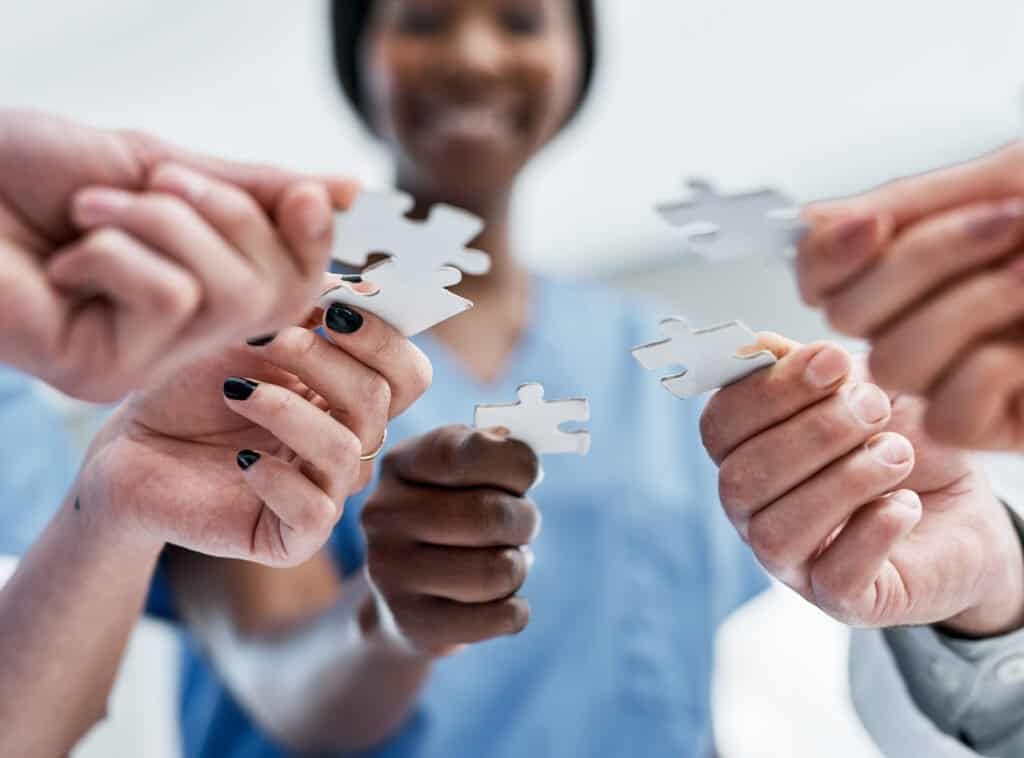 Closeup shot of a group of medical practitioners holding puzzle pieces.
