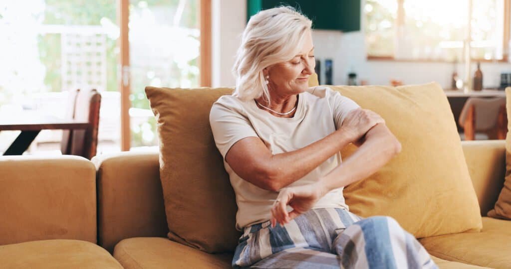 Happy, calm and mature woman in home, living room and smile for skin health in apartment or wellnes.