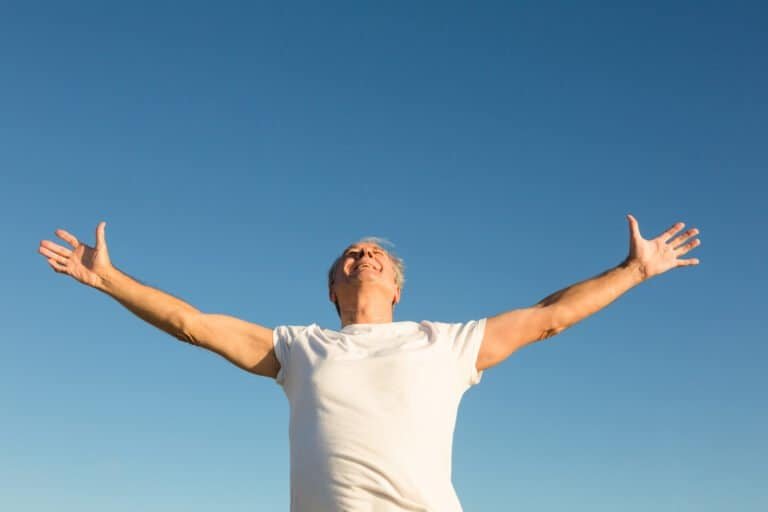 Low angle view of man with arms outstretched standing against clear sky