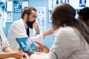 Medical professionals in a meeting examining organs on ct scan results. Skilled physicians and radiologists review x rays and hospital records to develop effective treatment plans. Collective work.
