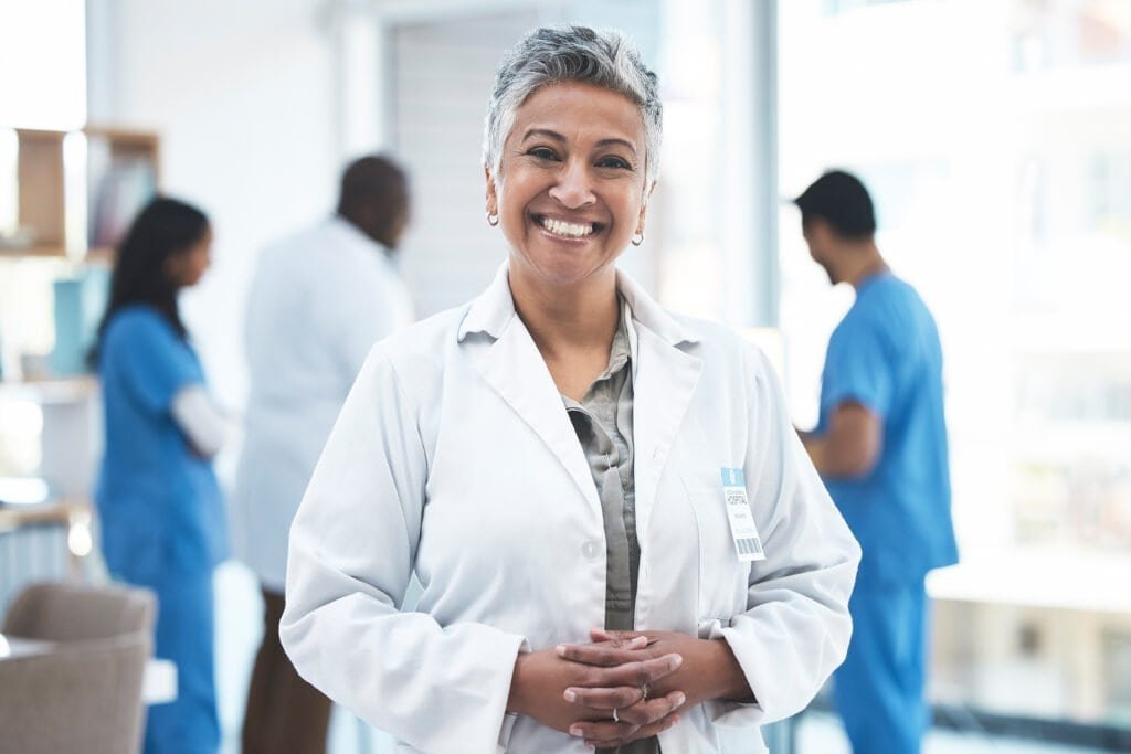 Senior doctor, woman and smile in clinic portrait for inspection, excited and vision for expert. Fe.