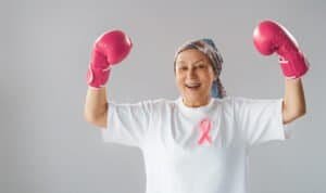 Woman in boxing gloves with a pink ribbon as a symbol of the fight against cancer. Increasing the level of knowledge about people who have overcome tumor diseases.