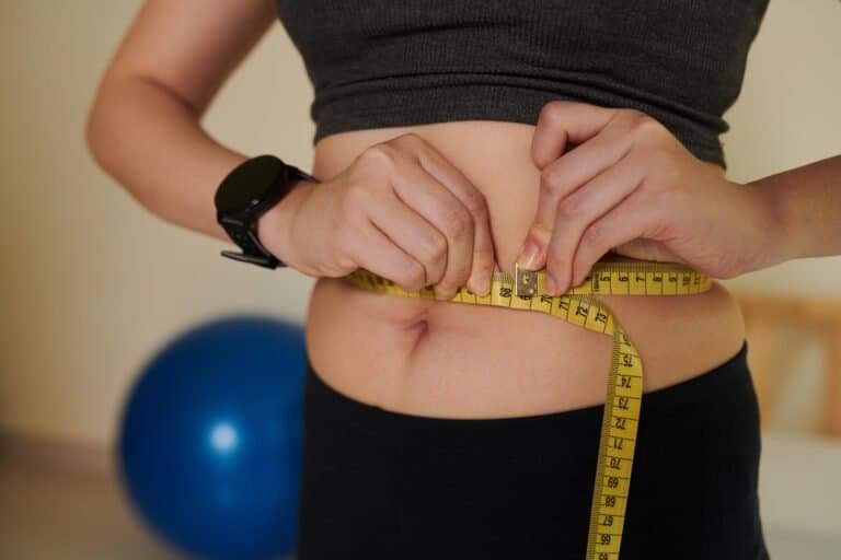 Cropped image of young woman measuring her waist after training at home, healthy lifestyle and loosing weight concept